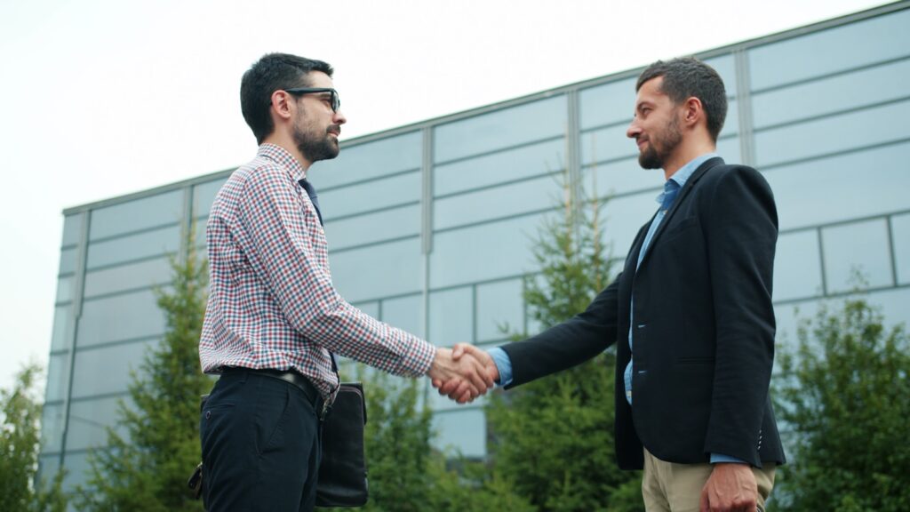 Two businessmen shaking hands outside modern building